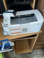HP LaserJet M110we printer with HP 63 cartridge box and silver mouse visible