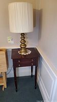Side table with brass lamp on top, full view