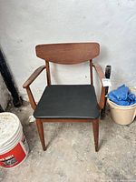 Front view of wooden armchair with black vinyl seat