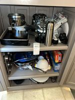 Cabinet with assorted cookware, blender, thermos and packaged items