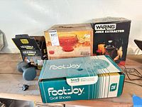 Boxes of Everlast ankle weights, Jeannette punch set, Waring juicer, FootJoy box of cords, dumbbell on shelf