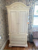 Front view of armoire showing doors closed and drawer layout