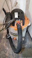 Front view of Ridgid shop vacuum with hose and nozzle attachment