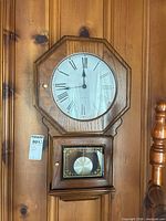 Full view of wall clock hanging on paneled wall