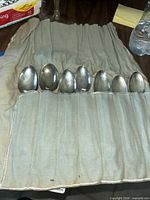 Cloth roll case partially open with six spoons visible
