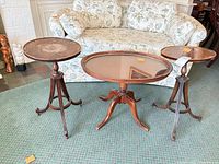 Front view of all three mahogany tables: oval coffee table center, two round pedestal side tables left and right