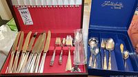 open wooden case displaying knives, forks, spoons