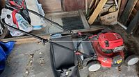 Left side view of mower showing handle, deck, rear bag, wheels