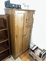 Full view of cabinet standing upright next to bookshelf and box