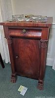 Front view showing drawer, door, columns, claw feet