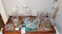 Overall view of all glassware on tray: Waterford pitcher, Mikasa bowl, decanters, pitchers, shakers, cut bowl, placemat