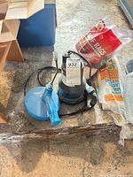 Wayne Vortex utility pump with blue hand drain snake and bag of shop rags on floor
