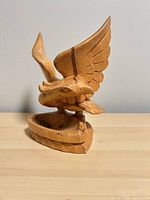 Front view of carved wood eagle ashtray on tabletop