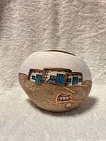 Front view of rounded ceramic vase showing Pueblo adobe scene with blue doors