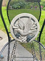 Front view of round concrete plaque showing dove, grapes, leaves relief