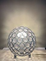Full view of spherical chrome and crystal disc table lamp on three feet with cord