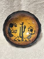 Front view of hand-painted terracotta bowl showing Kokopelli design