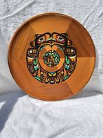 Full view of round cedar plaque showing painted motif and wood grain