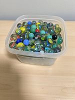 Square plastic container filled with assorted glass marbles