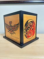 Three-quarter view of cedar box showing thunderbird and circular crest panels, signature visible