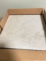 Open box showing beige marble-look ceramic tile surface