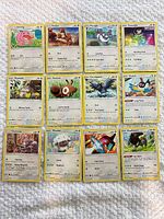 11 Pokémon cards laid out on white textured surface showing fronts