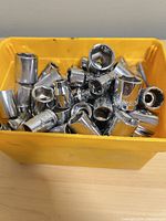 Front view of yellow bin filled with assorted metric sockets