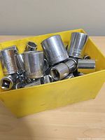 Top view of yellow bin filled with chrome sockets