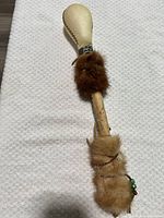 Full view of rattle showing head, handle, fur wraps