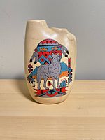 Front view of tan ceramic vase with wolf and Southwestern graphics