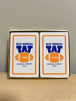 Two decks inside box showing card backs white with orange and blue borders