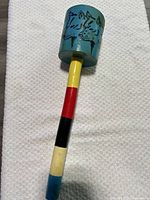 Full view of rattle showing painted head and multicolour handle