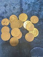 Group of 17 brass-tone tokens spread on fabric