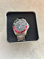 Front view of wristwatch seated in original RME tin showing dial, bezel, and bracelet