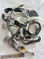 Pile of assorted wristwatches showing variety of styles, metals and straps