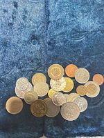 Group of approximately 22 mixed world coins on blue fabric