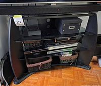 Front view of black TV stand with glass shelves