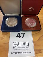 Open red and blue Royal Canadian Mint cases showing the Silver Maple Leaf coin and 1980 Polar Bear Silver Dollar