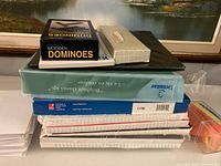 Stack showing dominoes box, storage box, binder, paper reams and page flags