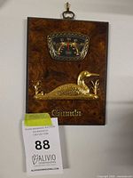 Front view of vintage wall plaque with gold-tone loon figure, thermometer dial, and Canada text