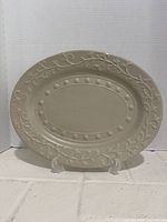 Full view of oval beige ceramic platter on stand