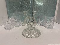 Group shot of all crystal items: four glasses, two double candlesticks, one lid