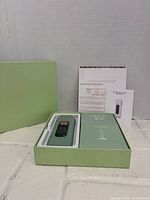 Open box showing green IPL device in tray alongside accessory compartment, manuals behind
