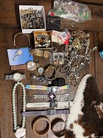 Overview of entire lot showing watches, necklaces, bracelets, rings, bangles and bead bag on wooden surface