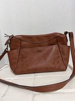 Front view of Rosetti brown faux leather crossbody bag showing overall shape, strap and embossing