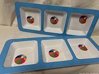 Two Swell melamine trays showing six square compartments with beach ball motifs