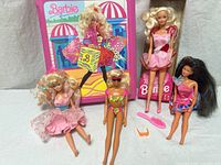 Group shot of four Barbie dolls, carrying case, comb, orange sunglasses
