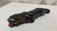 Full side view of glossy black ceramic panther figurine