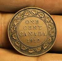 Reverse of 1912 Canada one cent coin on fingertip