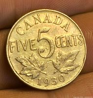 Reverse of 1930 Canada 5 cent coin showing denomination, maple leaves and date